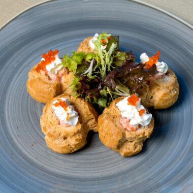 Elegant puff pastries topped with caviar and cream cheese, garnished with fresh greens.